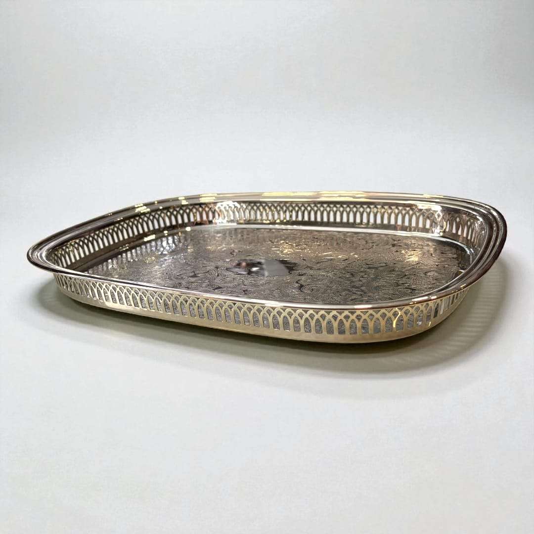 Detalle del grabado floral en la bandeja de metal plateada.