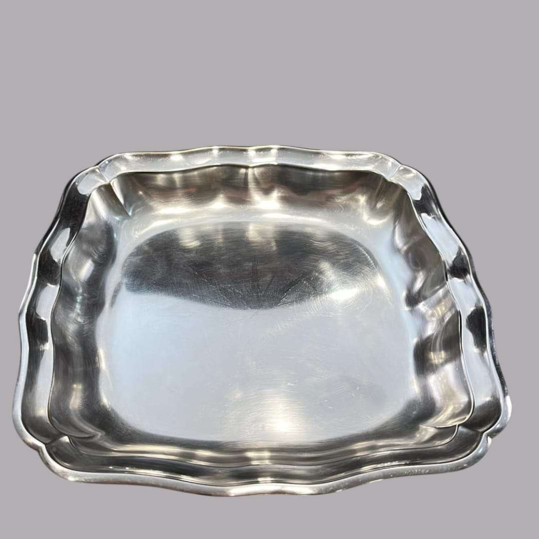 Vista lateral de la bandeja de metal plateado con patas, resaltando su diseño elevado y elegante.