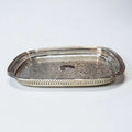 Bandeja de metal plateada grabada, elegante y artesanal con diseño floral y bordes calados, ideal para decoración de interiores refinada.