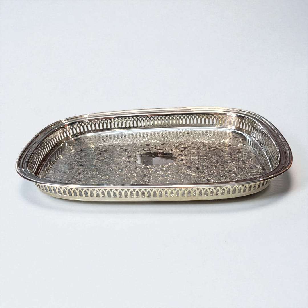 Bandeja de metal plateada grabada, elegante y artesanal con diseño floral y bordes calados, ideal para decoración de interiores refinada.