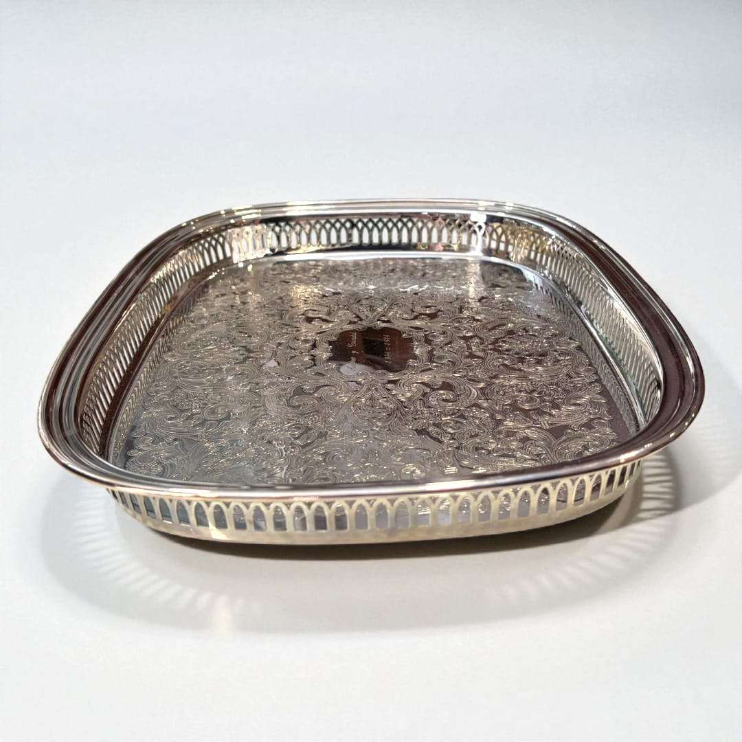 Bandeja de metal plateada grabada, elegante y artesanal con diseño floral y bordes calados, ideal para decoración de interiores refinada.