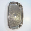 Bandeja de metal plateada grabada, elegante y artesanal con diseño floral detallado y bordes calados, ideal para decoración refinada del hogar.