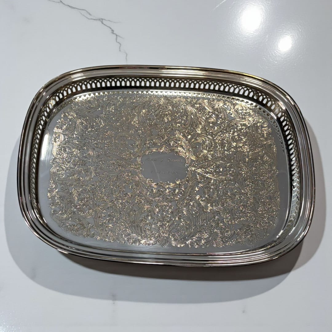 Bandeja de metal plateada grabada con bordes calados.