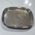 Bandeja de metal plateada grabada con bordes calados.
