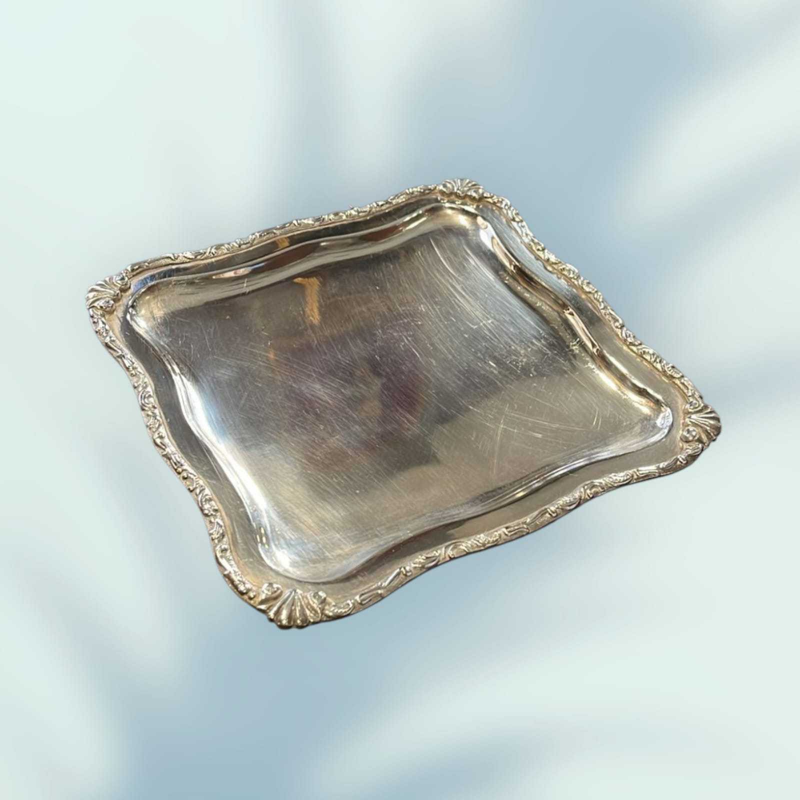 Elegante bandeja de metal plateado con diseño clásico y bordes decorativos, ideal para decoración de interiores estilo vintage.