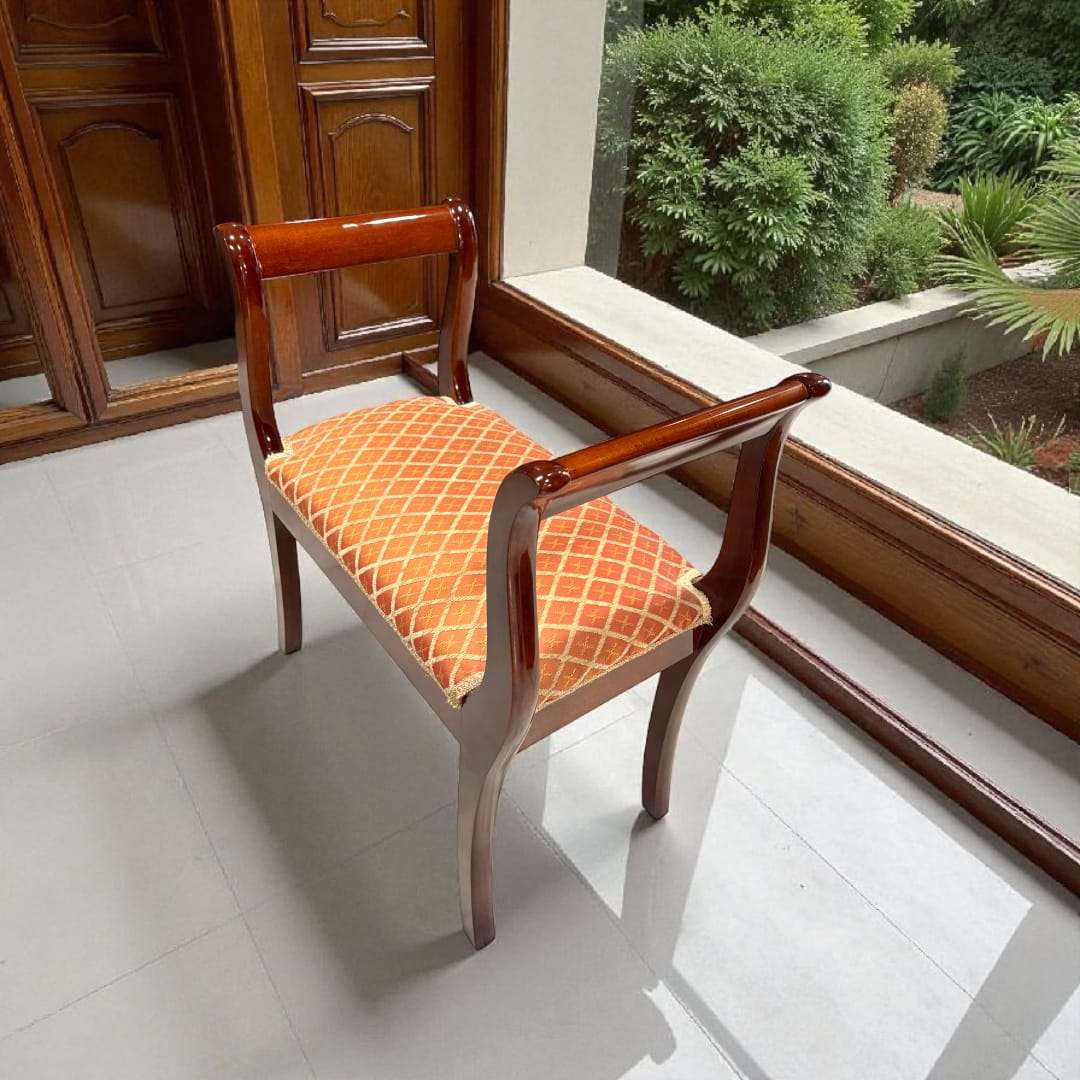 Banqueta de caoba con tapizado clásico en tonos anaranjados.