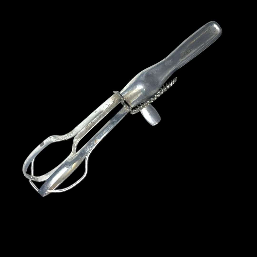 Vista lateral de la batidora manual antigua en metal brillante.