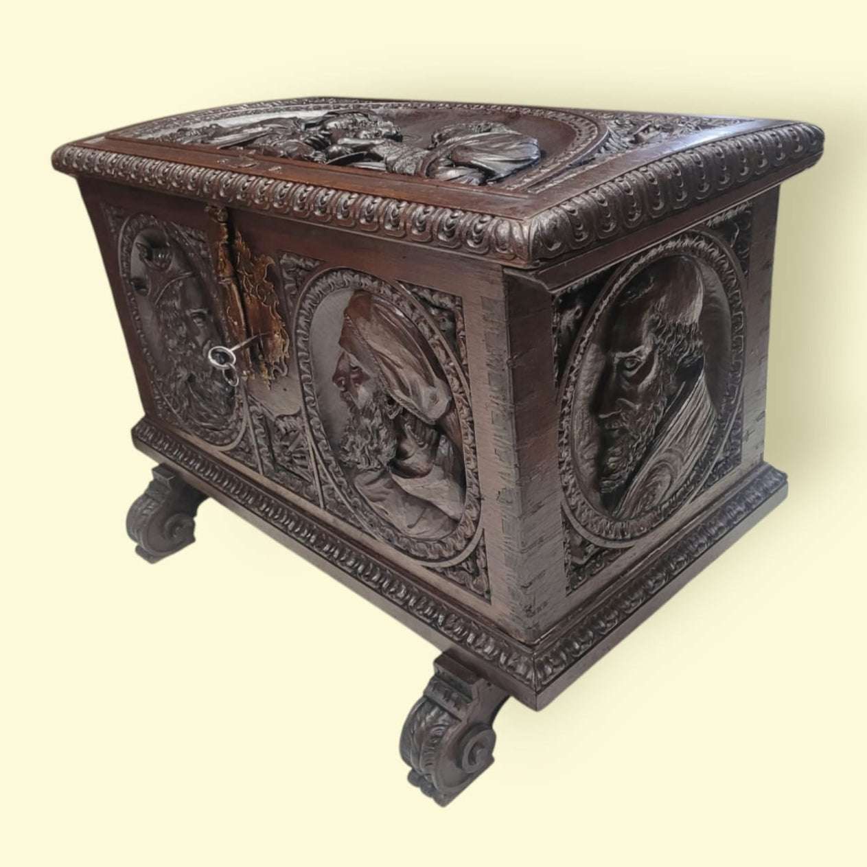 Baúl de cedro con tapa tallada y patas ornamentadas, diseño artesanal con relieves históricos, ideal para decoración y almacenamiento sofisticado.