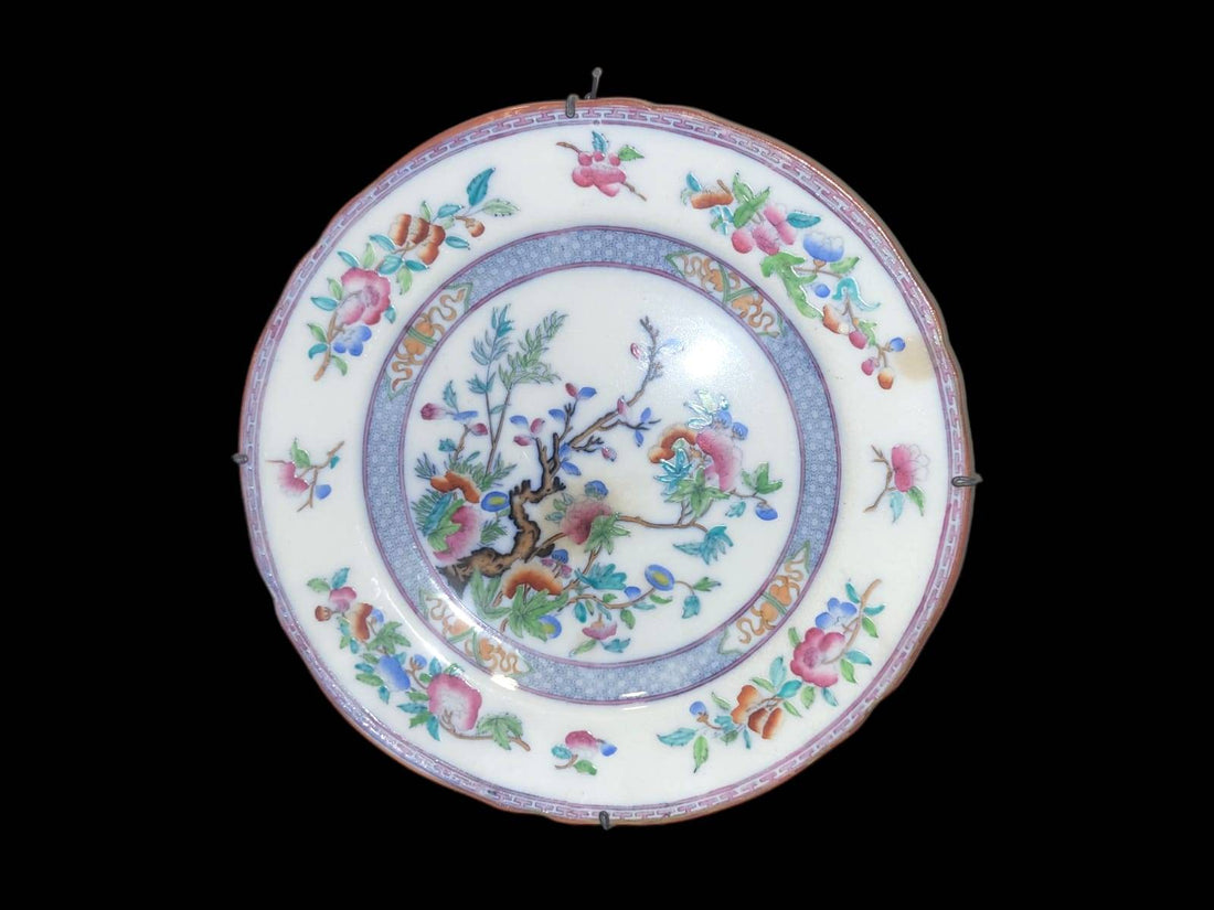 Plato de porcelana oriental pintado a mano con detalles florales únicos en tonos vivos, ideal para decoración de interiores elegantes.
