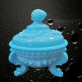 Bombonera de opalina azul con tapa y diseño vintage, decorada con relieve de conchas y base de tres patas curvas. Ideal para decoración elegante.