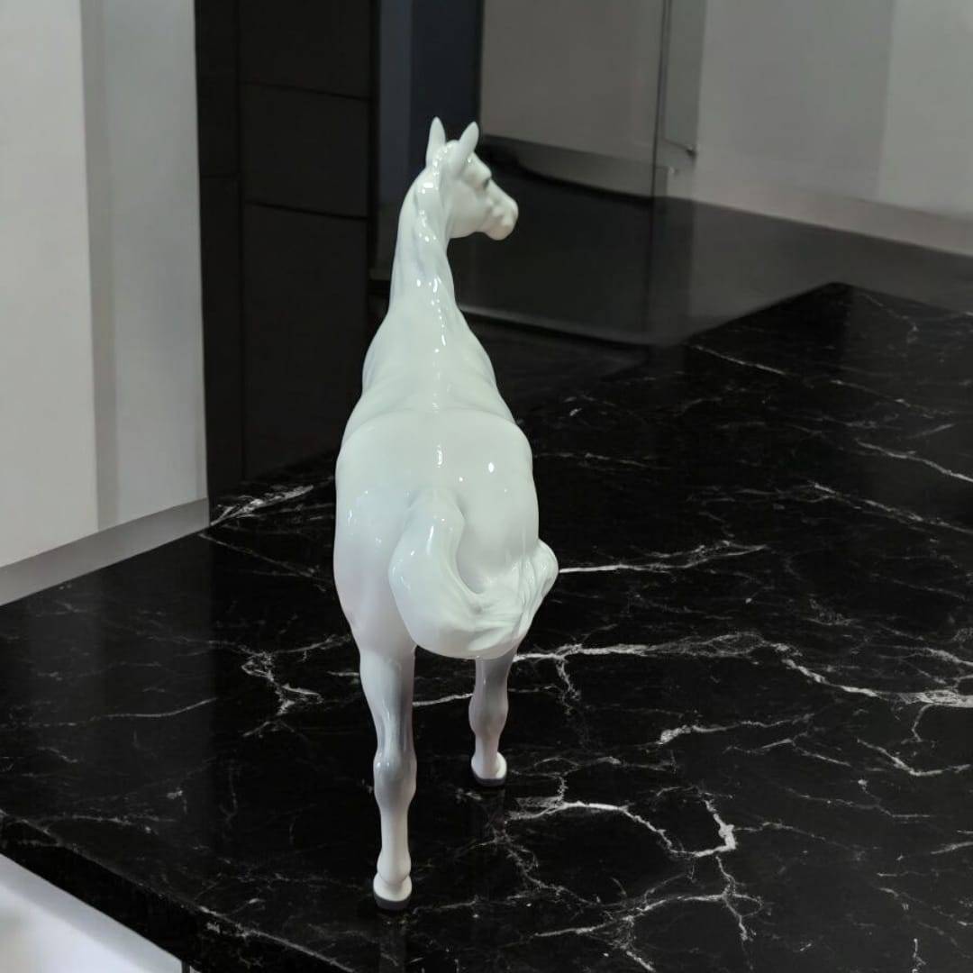 Caballo de porcelana Beswick blanco con detalles realistas, sobre superficie de mármol negro. Elegancia ecuestre clásica para decoración de interiores.