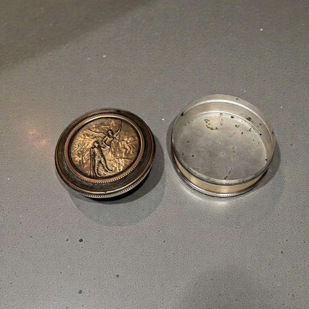 La caja redonda de metal con relieve es una pieza decorativa versátil y atemporal, ideal tanto para uso personal como para lucir en una vitrina. 