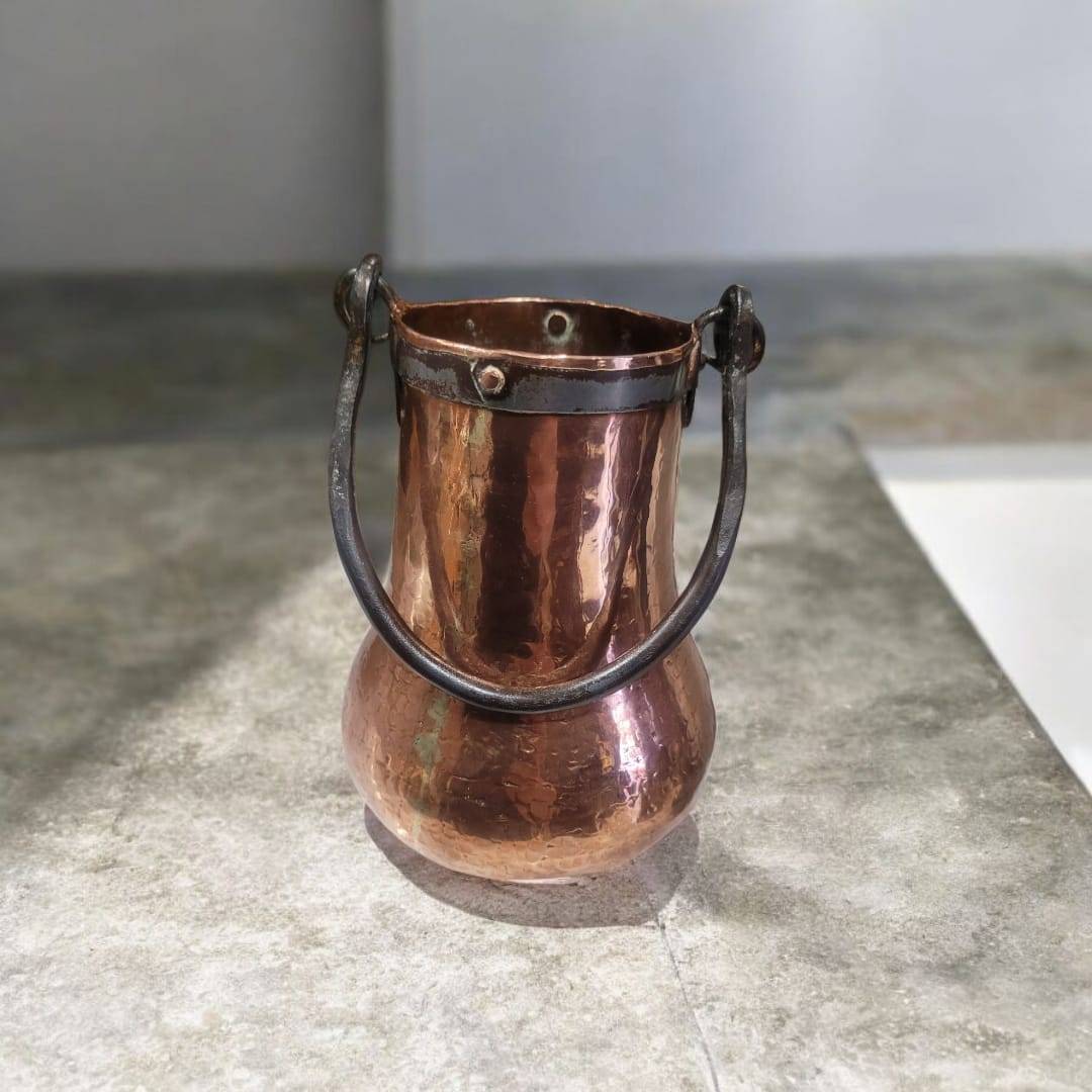Herrada de cobre antigua hecha a mano en forma de calabaza con acabado martillado y asa de hierro forjado. Ideal para decoración vintage de interiores.