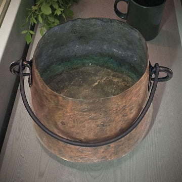 Caldero de cobre antiguo con asa de hierro forjado.