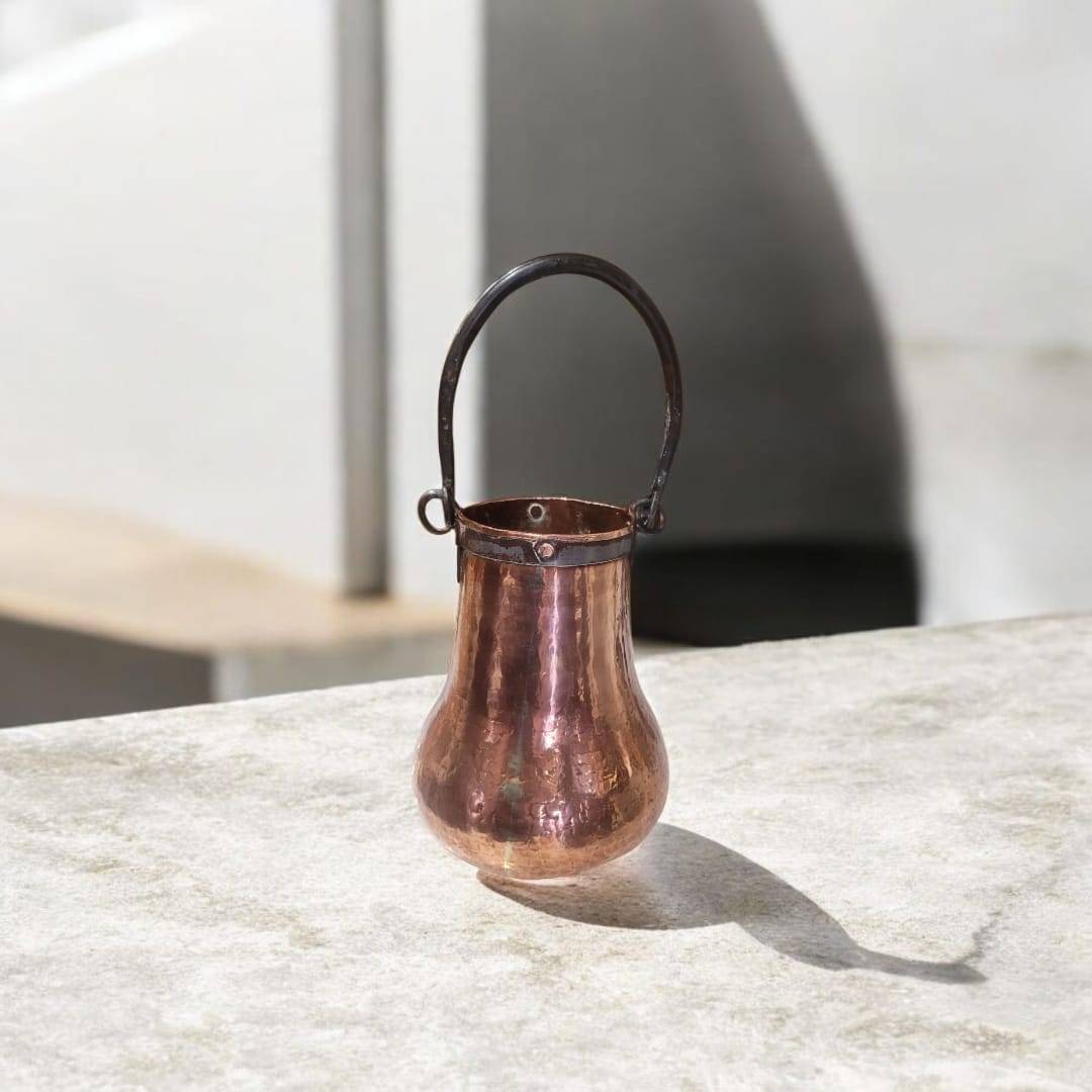 Herrada de cobre antigua hecha a mano en forma de calabaza con acabado martillado y asa de hierro forjado. Ideal para decoración vintage de interiores.