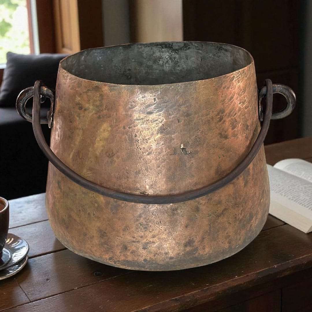 Caldero de cobre antiguo con asa de hierro forjado.
