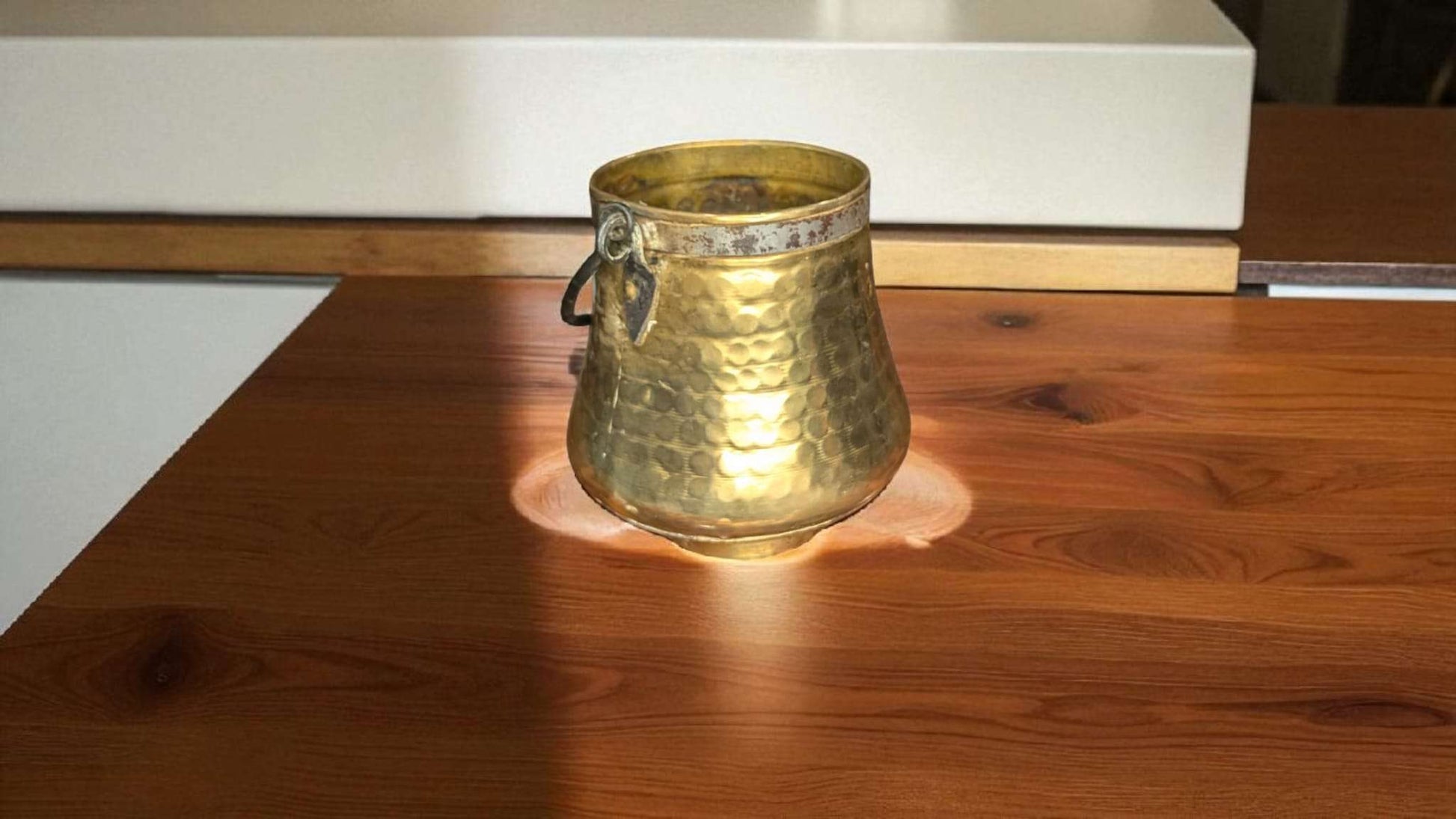 Caldero Antiguo de Metal Dorado con Asa de Forja – Elegancia sobre mesa de madera, ideal para decoración rústica en interiores de hogar y jardín.