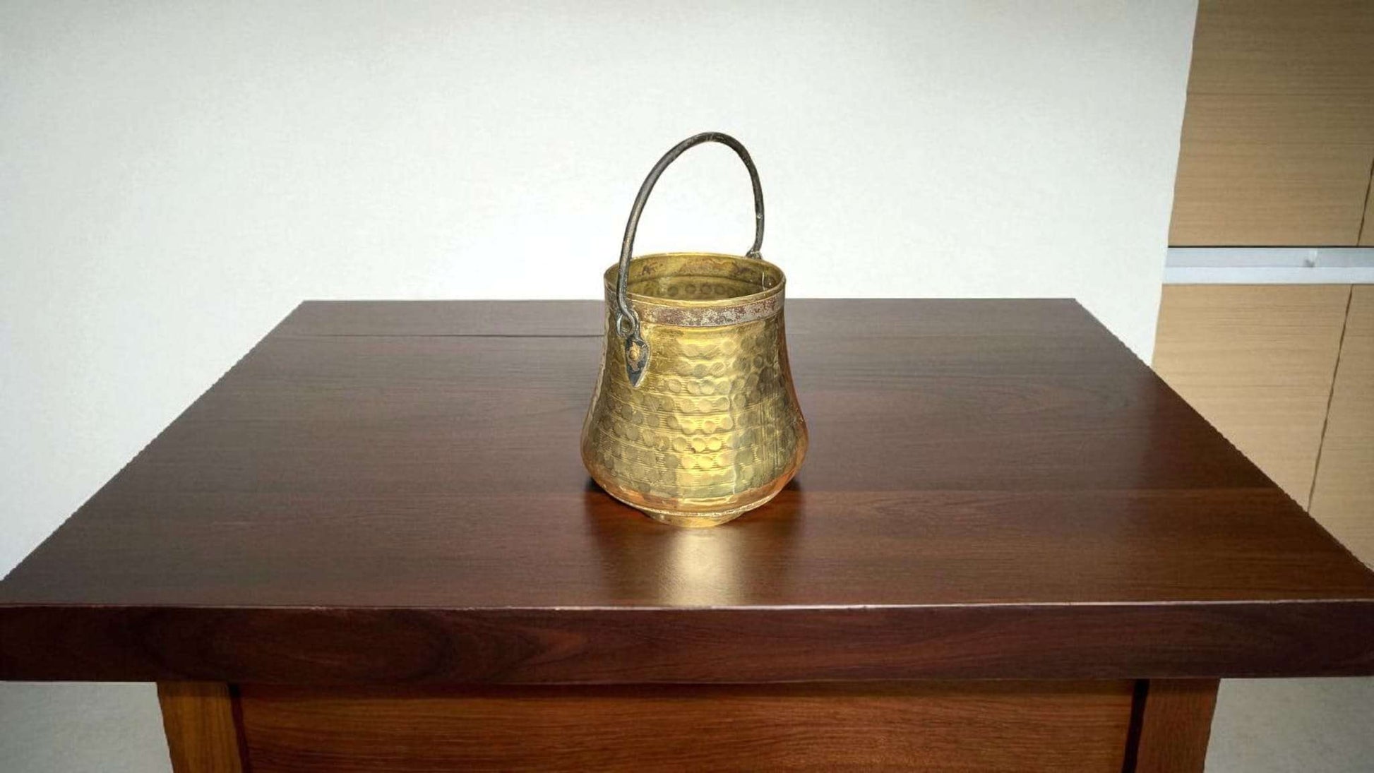 Caldero Antiguo de Metal Dorado con Asa de Forja sobre mesa de madera oscura, ideal para decoración vintage en interiores elegantes.