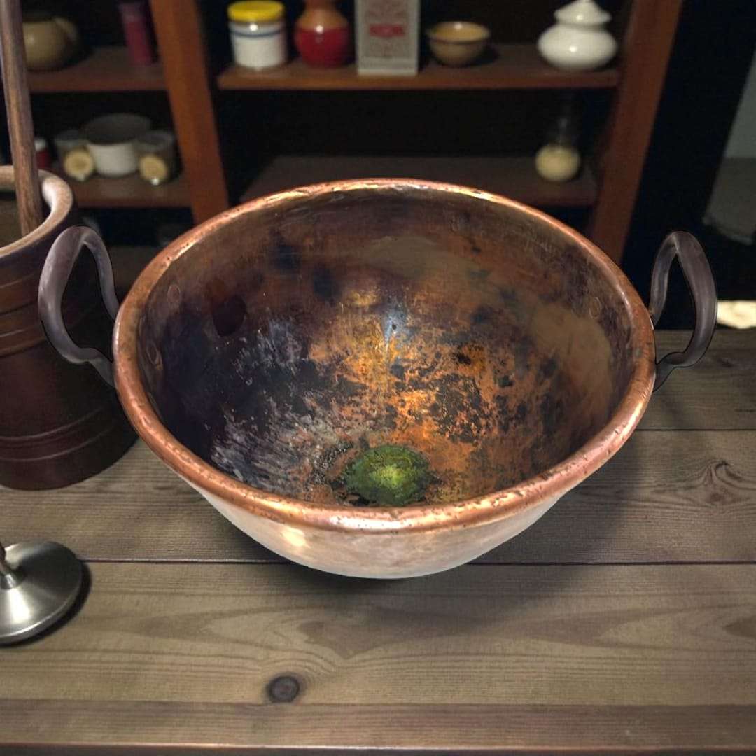 Detalle de las asas de forja remachadas en caldero de cobre.