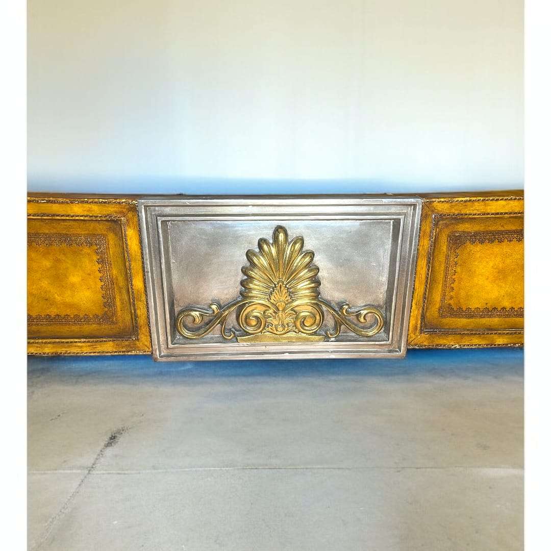 Detalle central del pie de la cama con ornamento plateado y dorado.