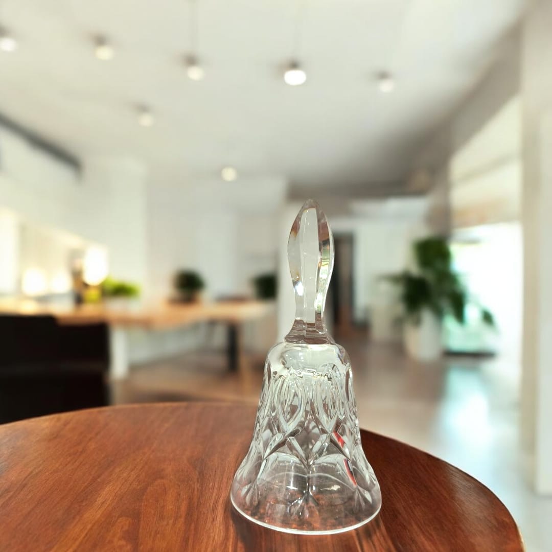 Campana de cristal tallado con diseño clásico sobre mesa de madera, ideal para decoración elegante en interiores modernos.