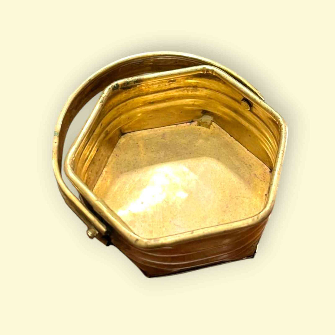 Canasta de metal hexagonal con acabado dorado brillante y asa fija, ideal para decoración o almacenamiento funcional.