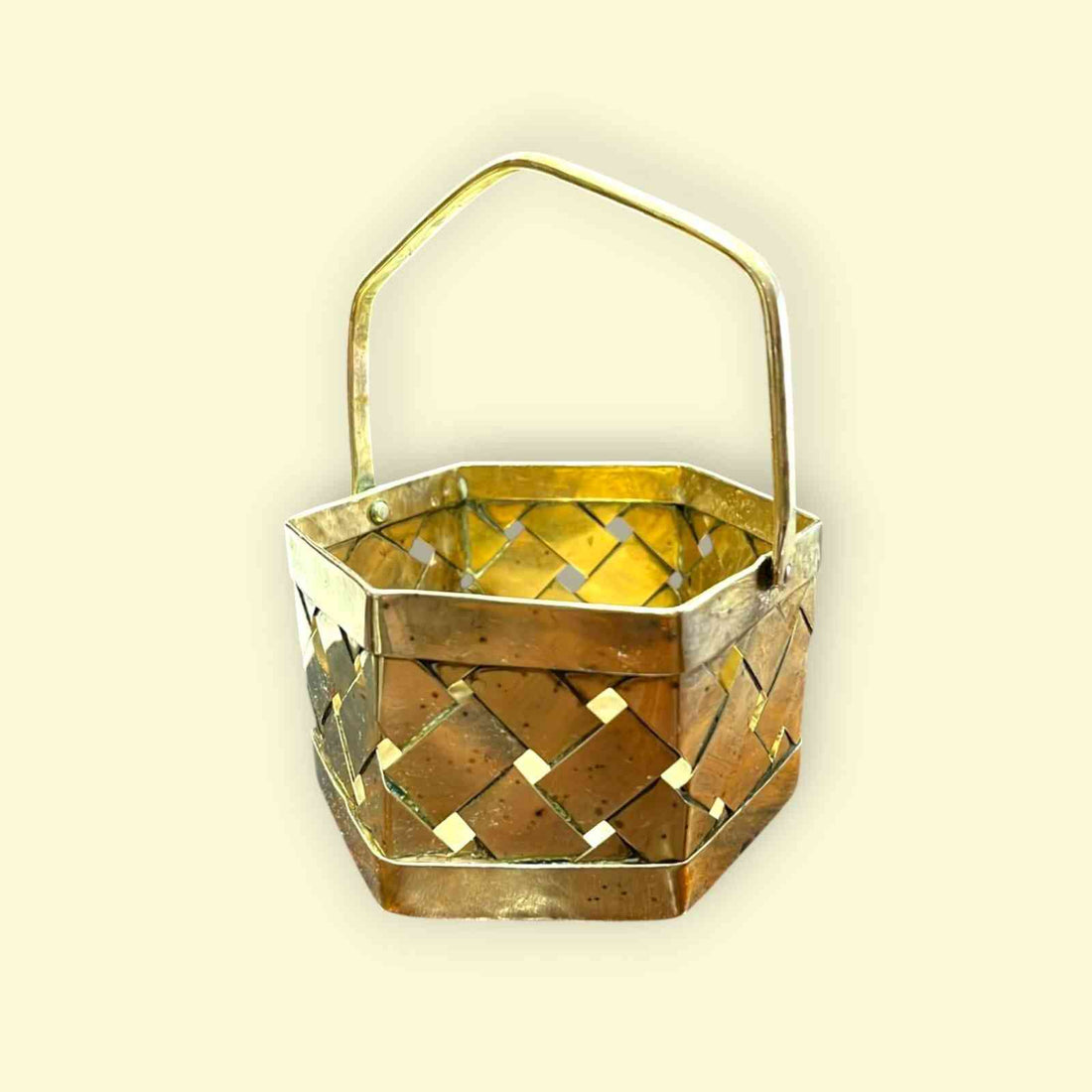 Canasta de metal hexagonal con acabado dorado brillante y asa fija, ideal para decoración o almacenamiento funcional.