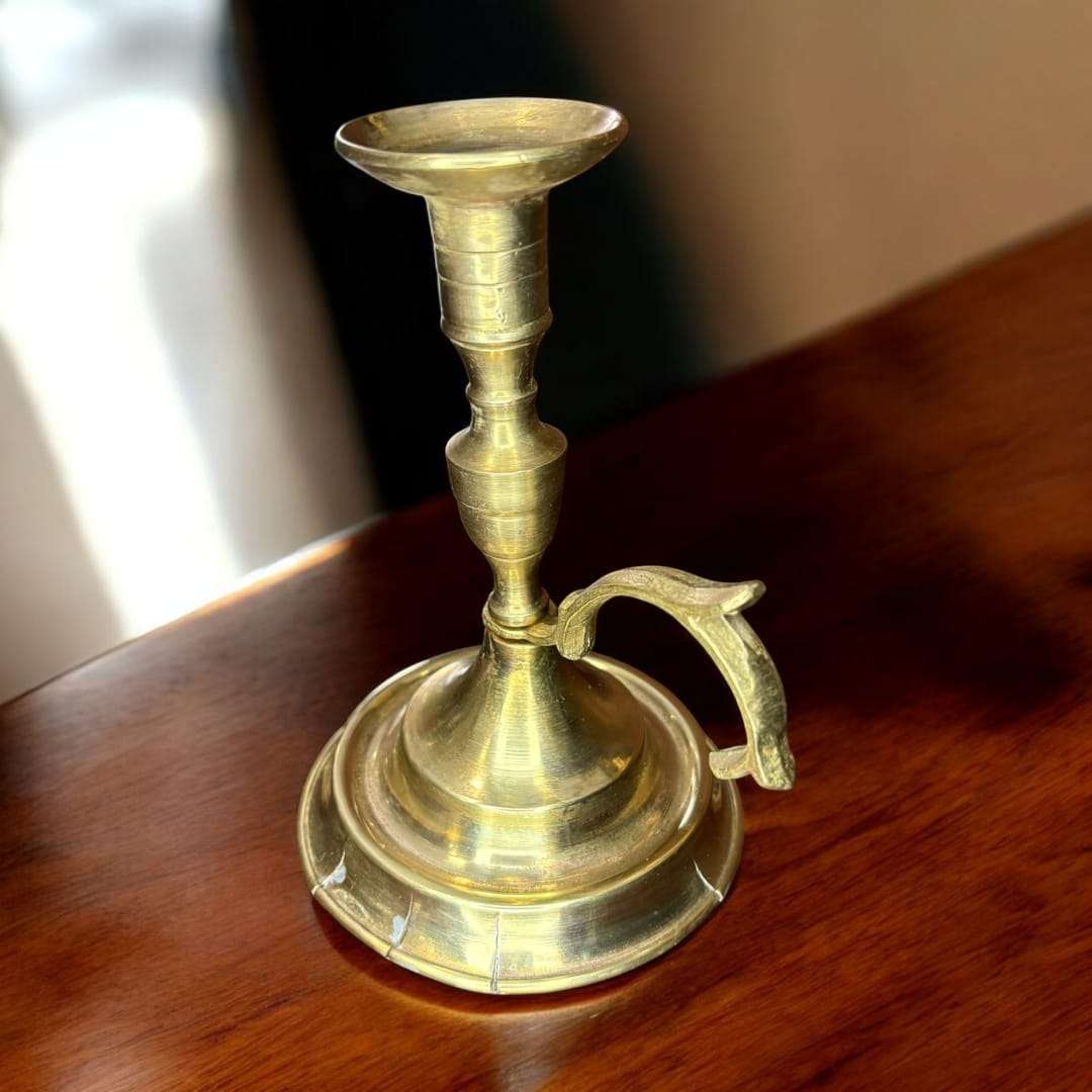 Esta Palmatoria de metal dorado no solo iluminaba espacios, sino que aportaba estatus, calidez y solemnidad, siendo un objeto imprescindible antes de la llegada de la luz eléctrica.