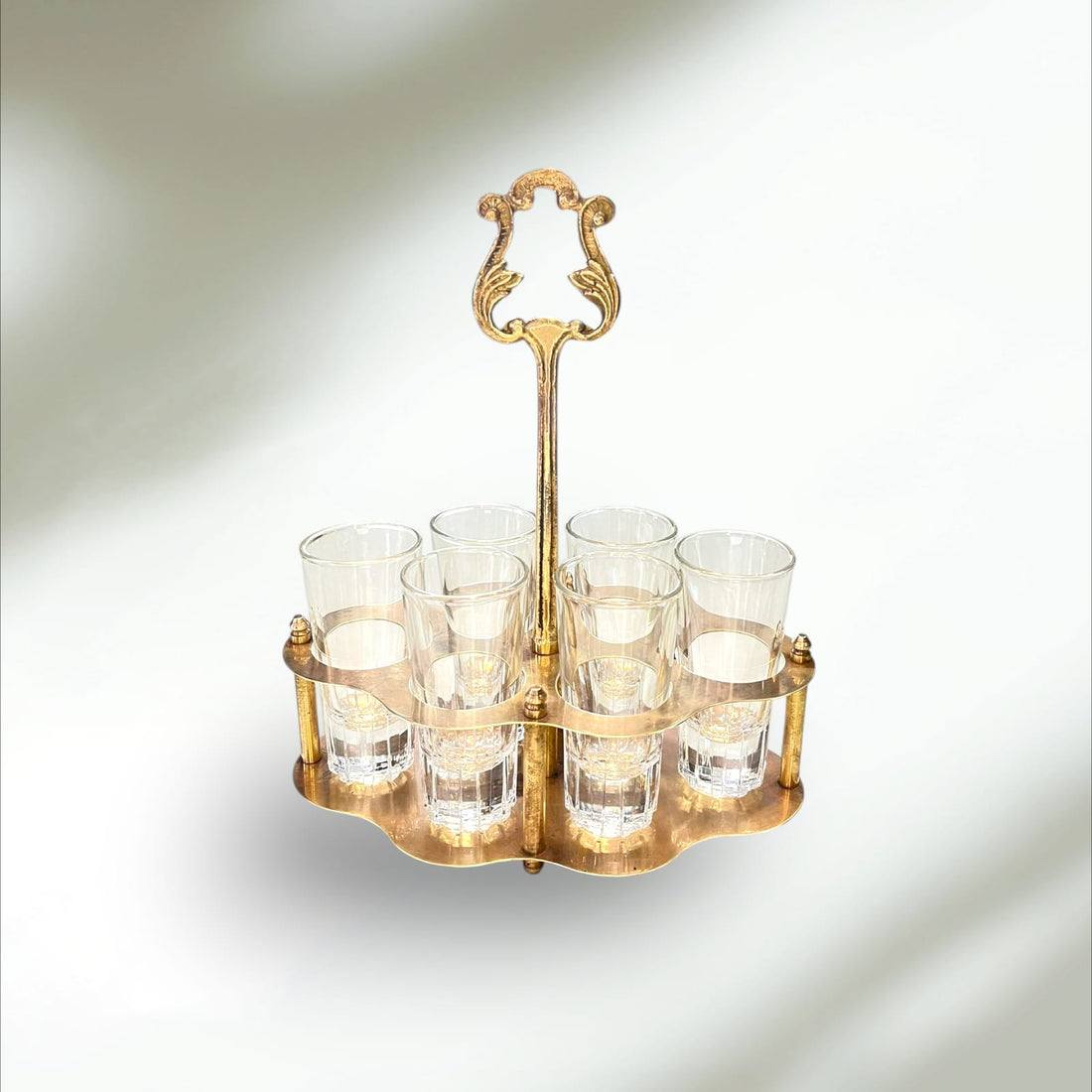 Cañero de metal dorado con seis vasos de cristal vintage, ideal para decoración de hogar o bar con estilo retro elegante.