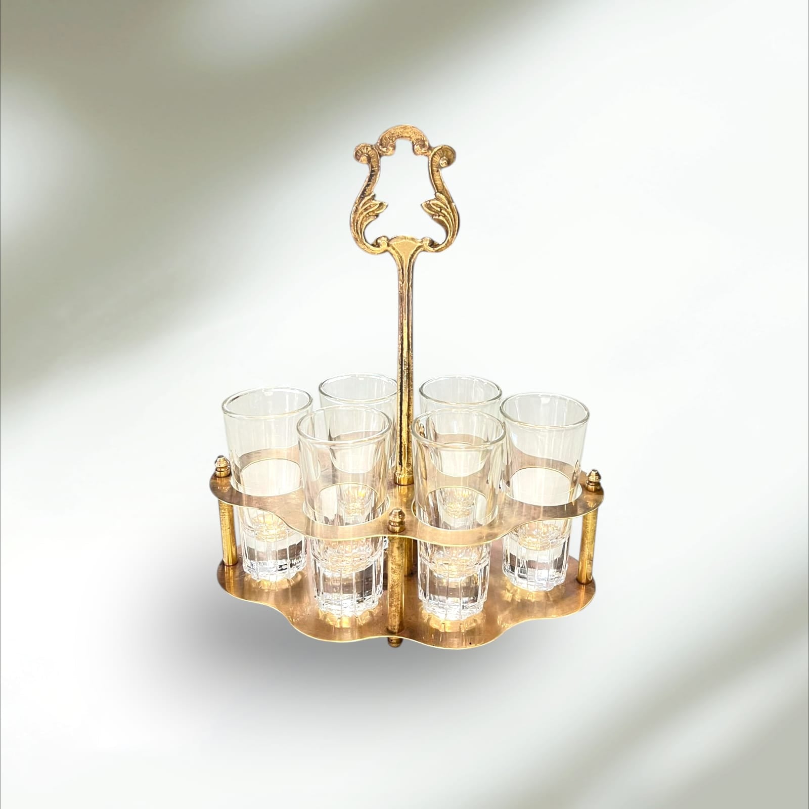 Cañero de metal dorado con seis vasos de cristal vintage, ideal para decoración de hogar o bar con estilo retro elegante.