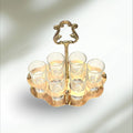 Cañero de metal dorado con diseño vintage y seis vasos de cristal transparente, ideal para decoración de hogar o bar con estilo retro.