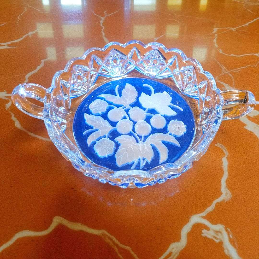 Primer plano de una compotera individual mostrando asa y borde facetado.