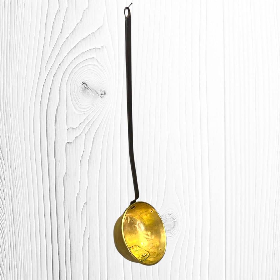 Gran cazo antiguo de metal dorado y hierro forjado con mango largo, ideal para decoración rústica en cocinas o paredes vintage.