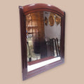 Espejo decorativo de caoba con cristal biselado y marco superior arqueado, ideal para ambientes sofisticados y decoración tradicional.