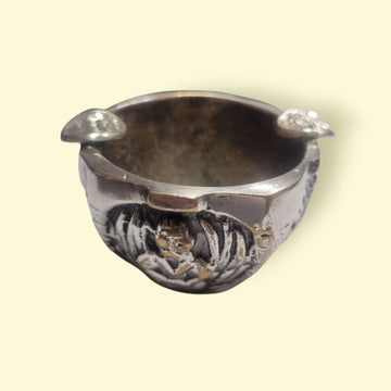 Cenicero flor de metal plateado multifuncional con diseño floral ALMAZÁN, detalle frontal con relieves decorativos en bronce.