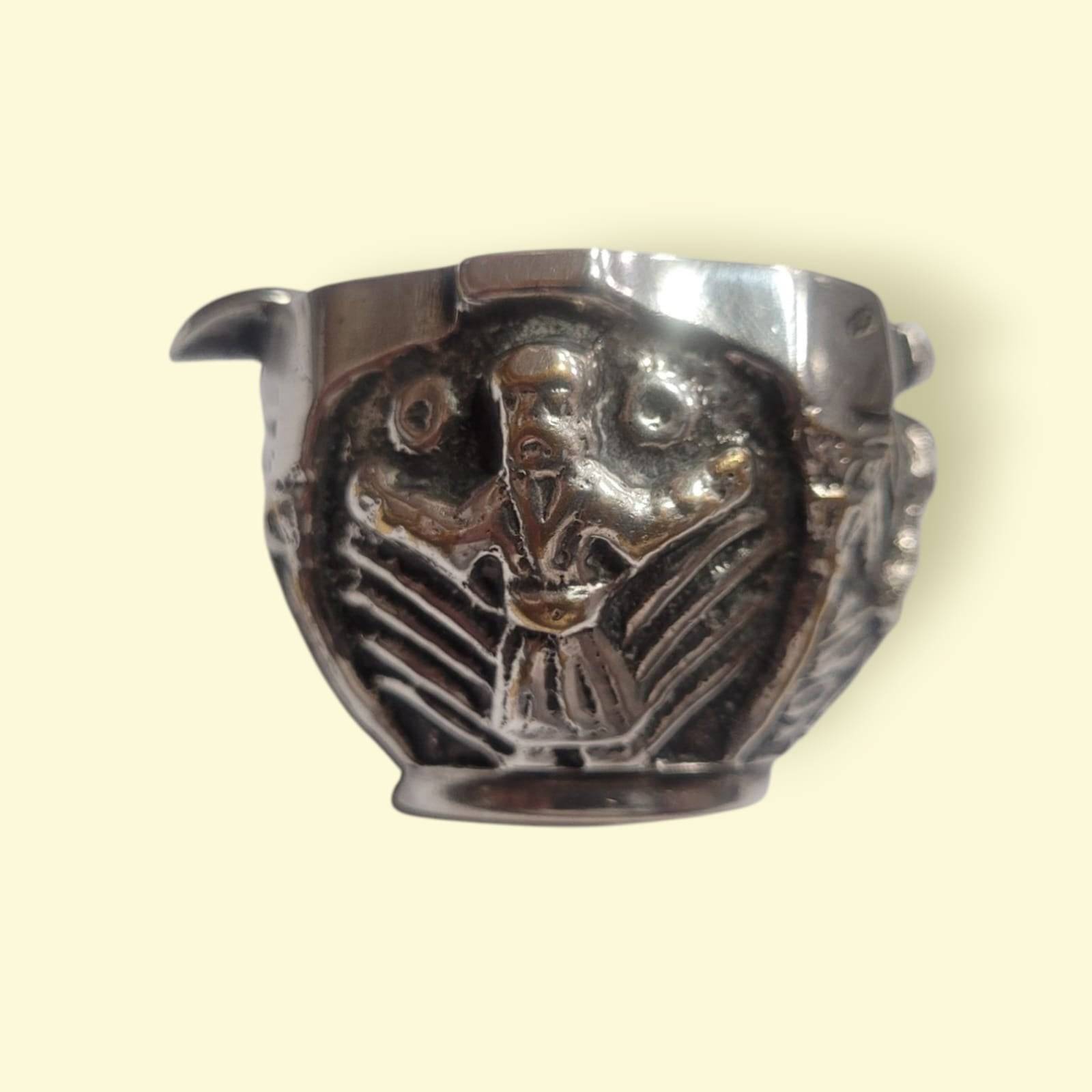 Cenicero flor de metal plateado con diseño floral y figura masculina en relieve, ideal para amantes de piezas únicas y decorativas.