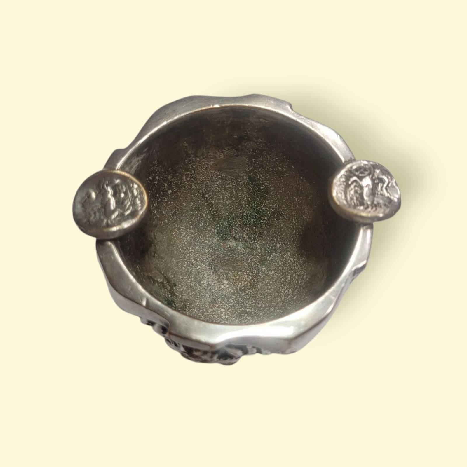 Vista superior del cenicero de bronce plateado ALMAZÁN con soportes decorativos y acabado envejecido, diseño floral artesanal.