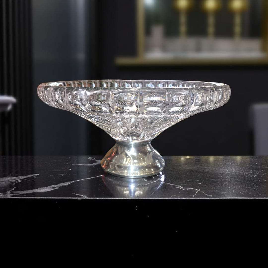 Centro de mesa de cristal con base de plata sobre mármol oscuro