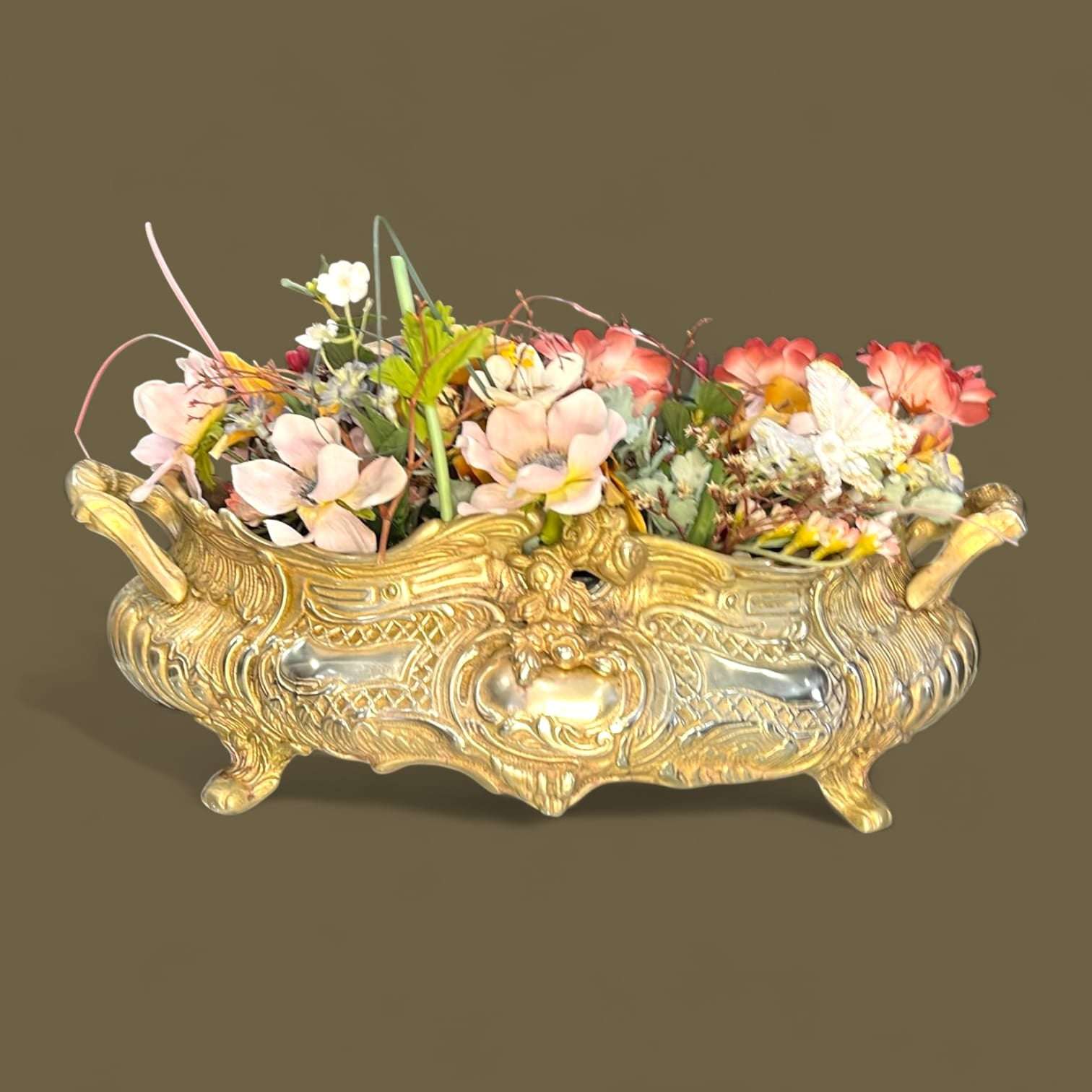 Este Centro de mesa floral de bronce destaca por su cuidada ejecución artística y su marcada inspiración Art Nouveau, visible en cada uno de sus relieves curvos y motivos vegetales.