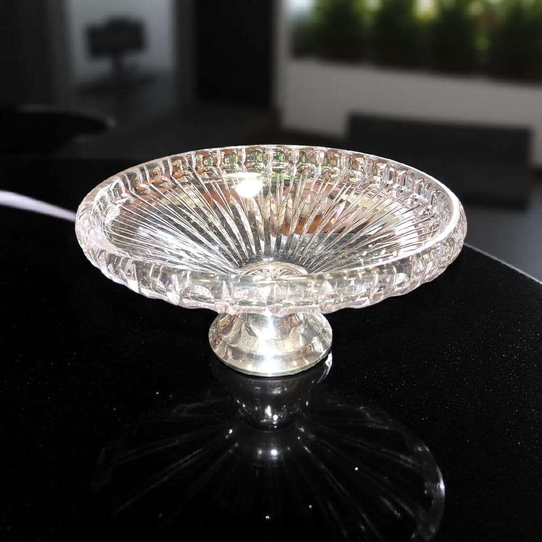 Centro de mesa de cristal con base de plata sobre mármol oscuro