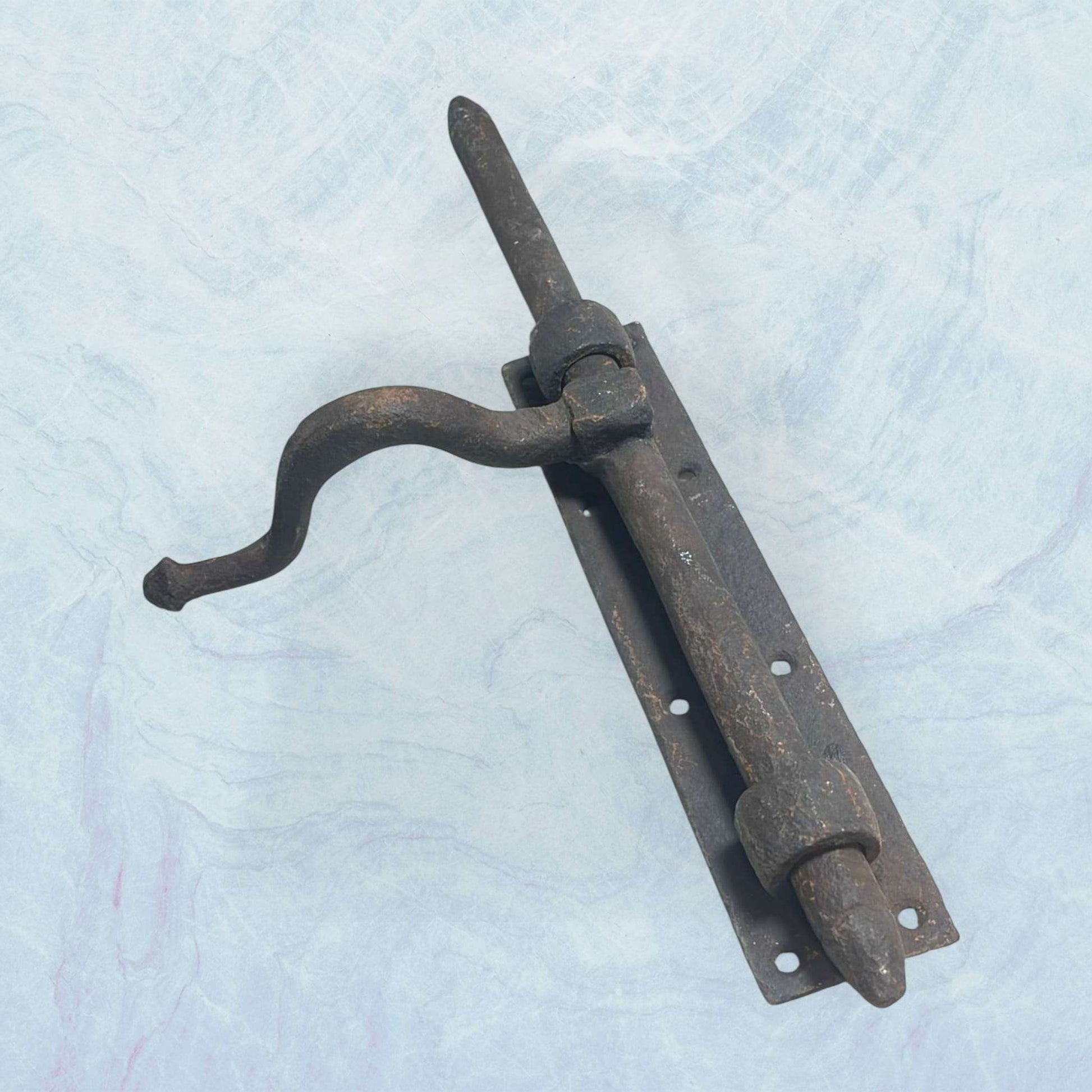 Cerrojo antiguo de forja artesanal con manilla curvada.