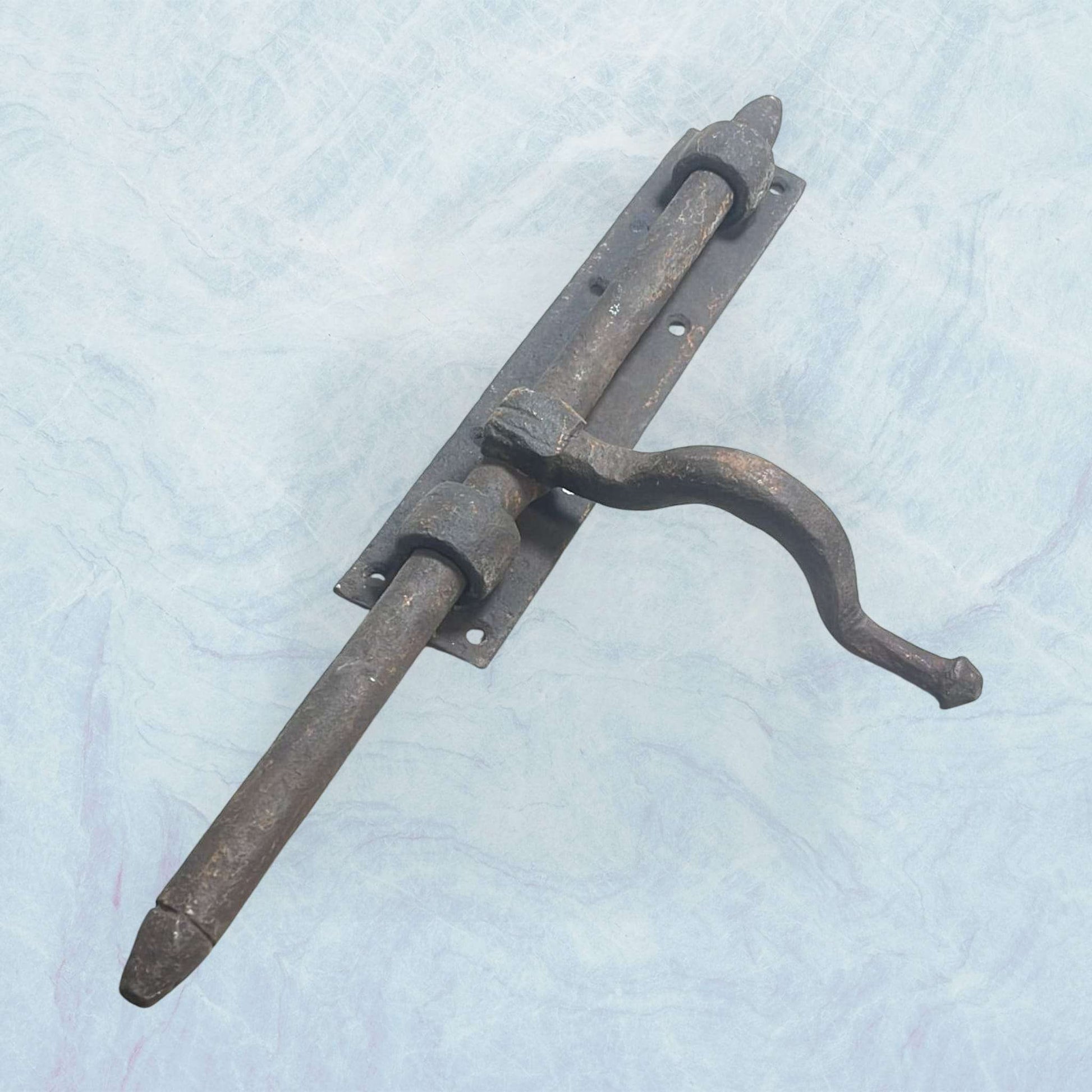 Cerrojo antiguo de forja artesanal con manilla curvada.