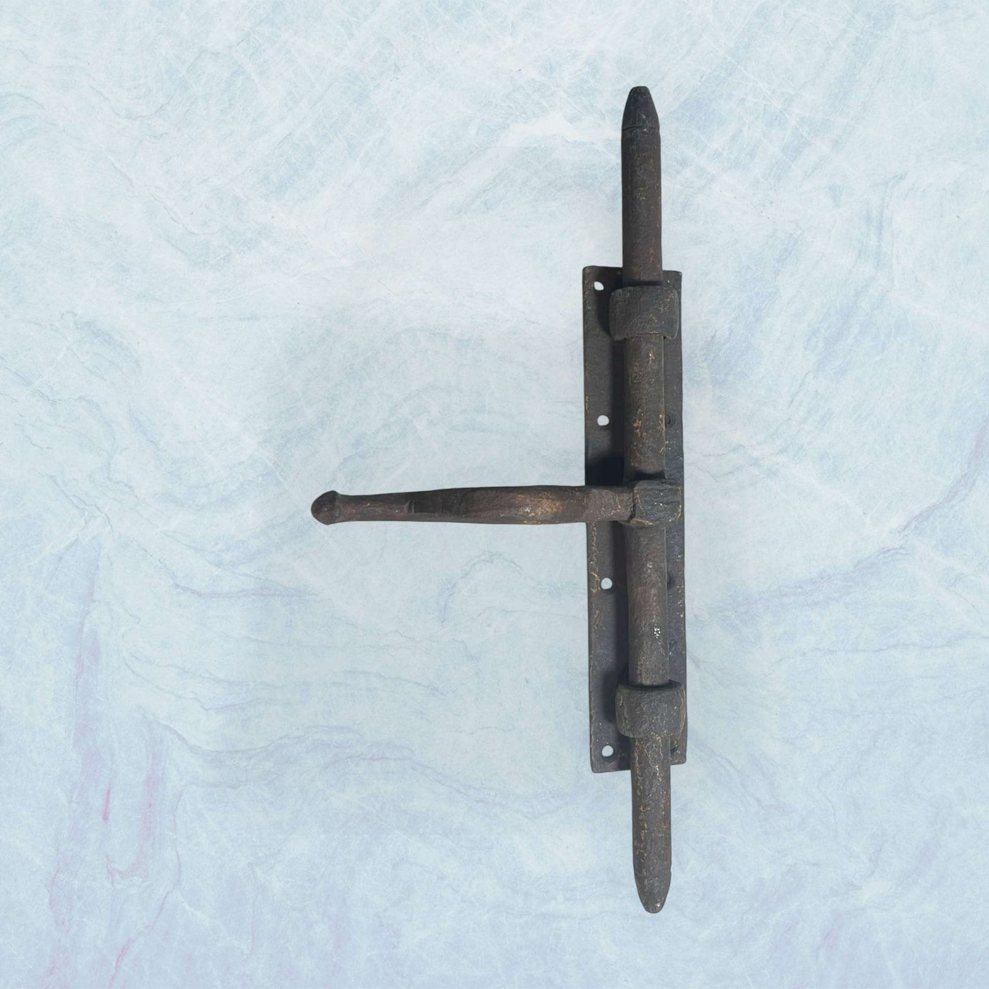 Cerrojo antiguo de forja artesanal con manilla curvada.