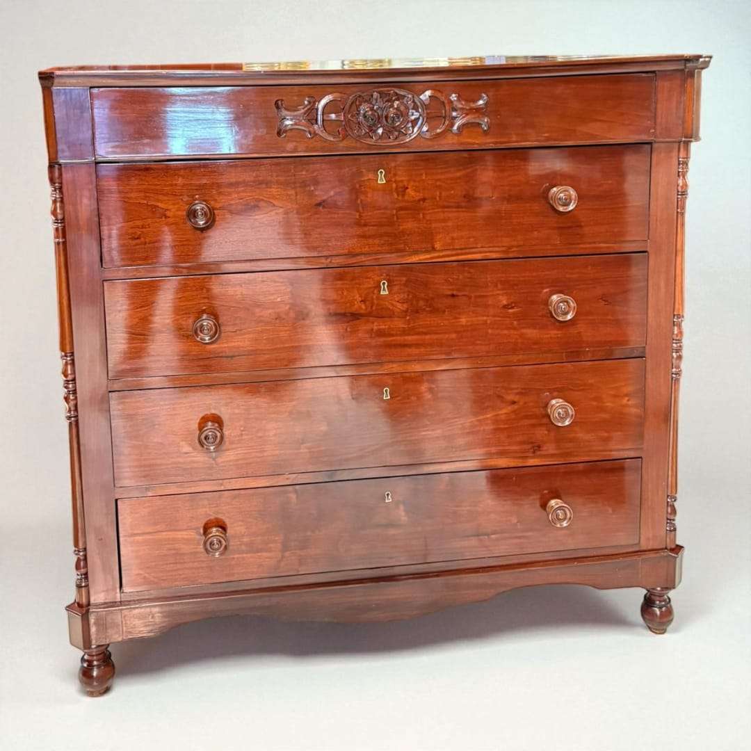 Realizada en madera maciza de caoba y conservando su acabado brillante de época, esta Cómoda destaca por sus líneas elegantes, sus detalles artesanales y la presencia imponente que aporta a cualquier estancia. 