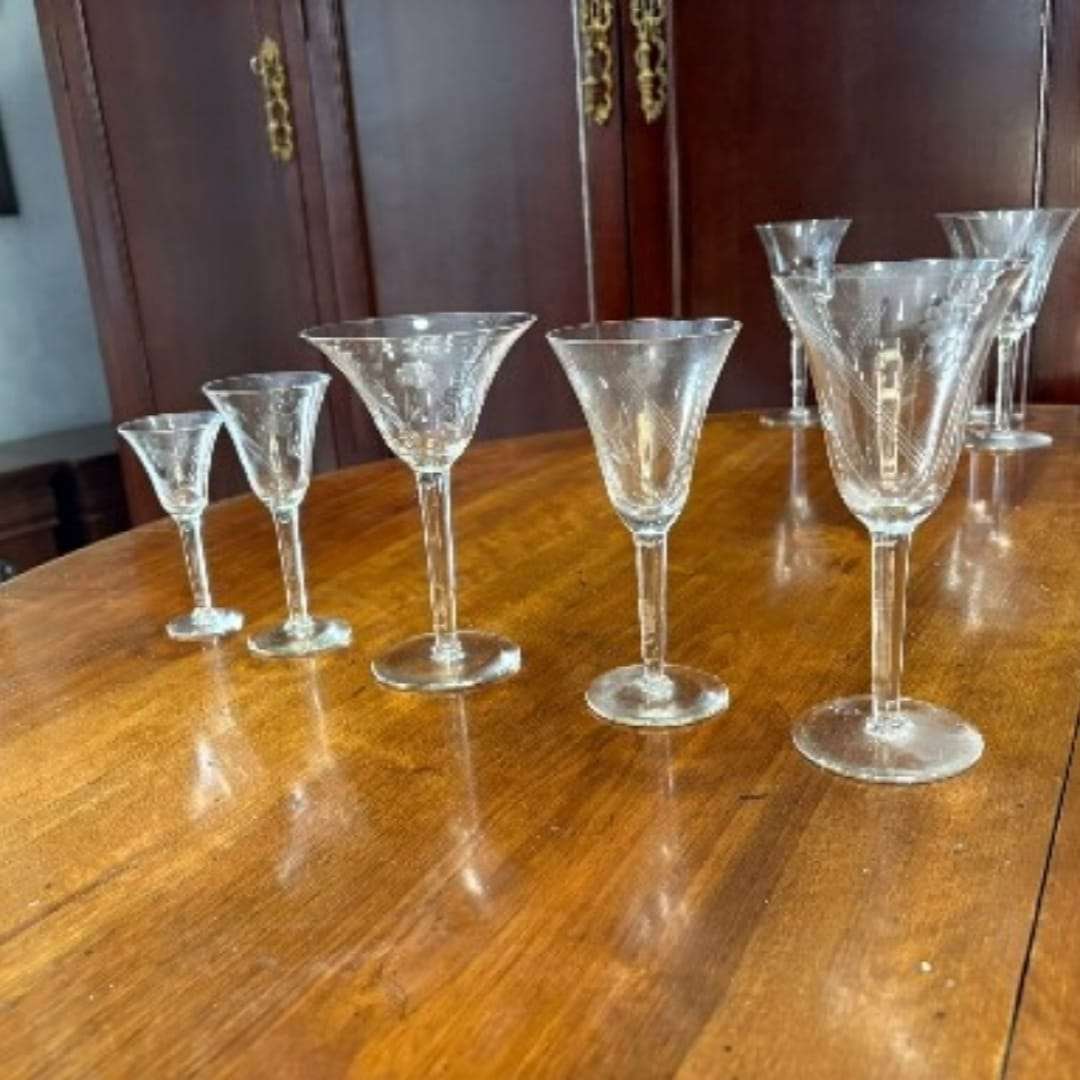 Copas de cristal tallado alineadas en orden de tamaño, pertenecientes a un juego de cristalería antigua decorativa.