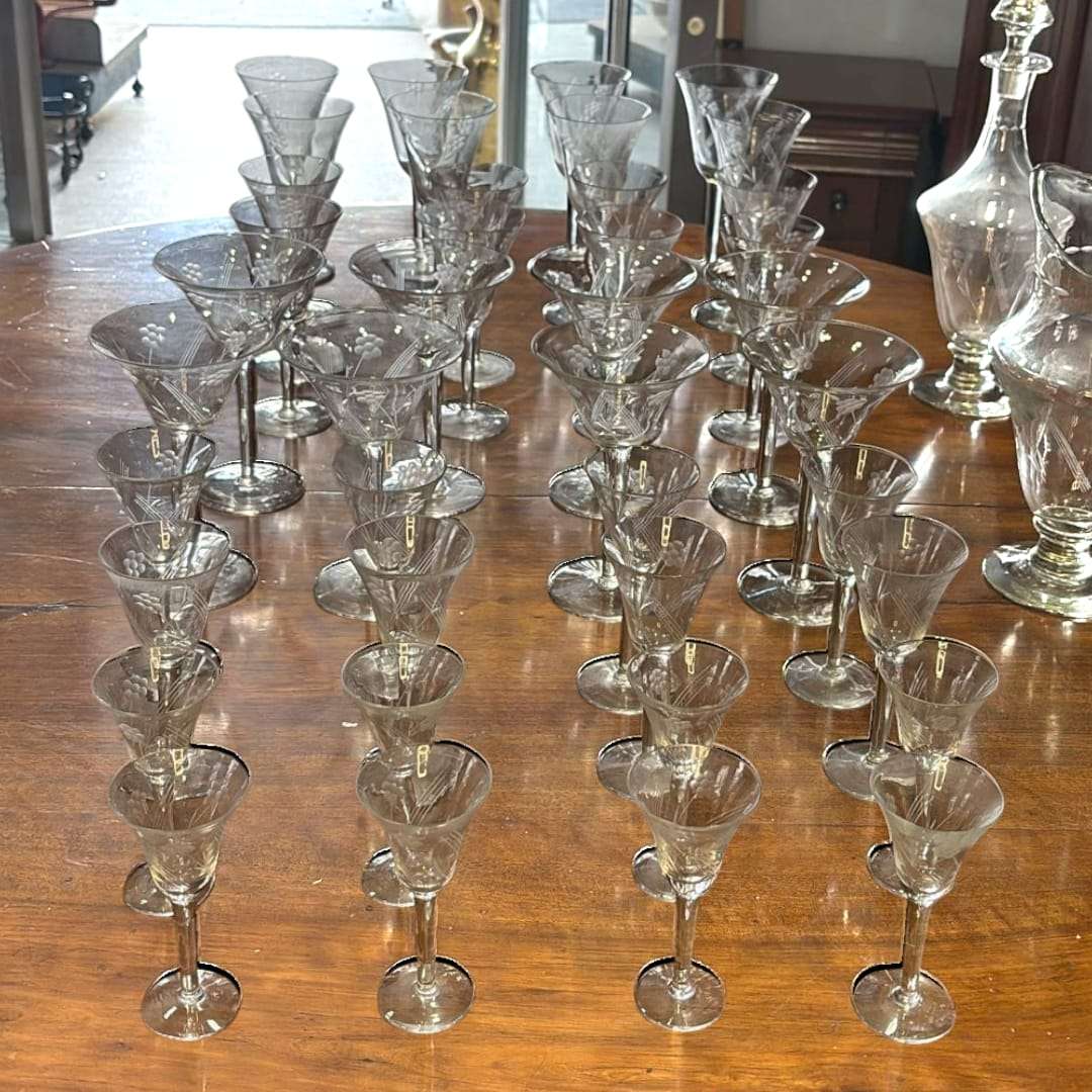 Vista superior del juego de copas talladas de cristal antiguo con licorera, ideal para decoración de estilo clásico.