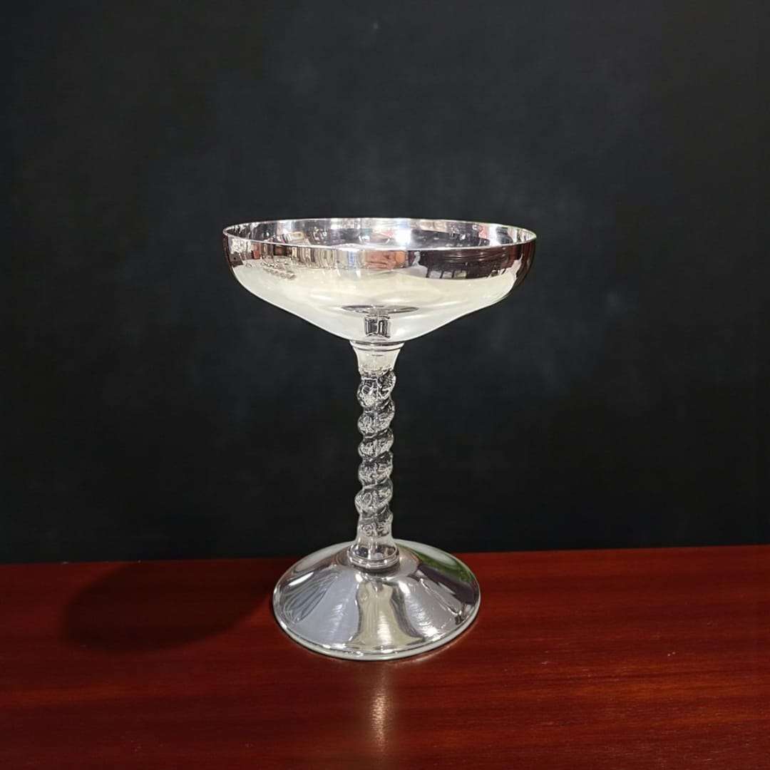 Copas plateadas brillantes sobre mesa de madera oscura.