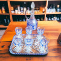 Licorera con seis copas de cristal azul tallado sobre bandeja, pieza decorativa refinada para espacios de estilo clásico o retro.