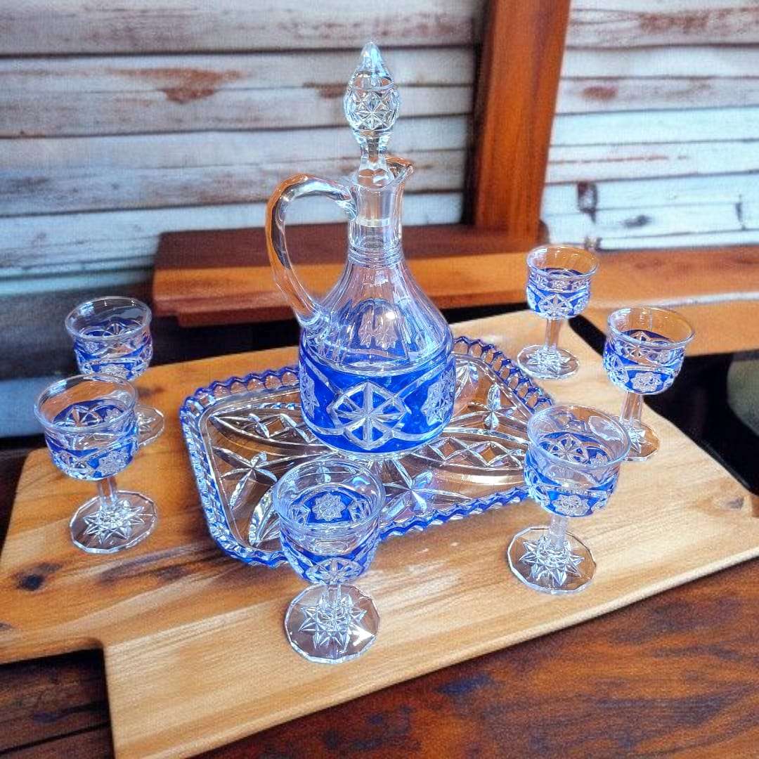 Set de licorera y seis copas de cristal azul tallado con diseño clásico, presentado sobre bandeja de cristal, perfecto para decoración vintage.