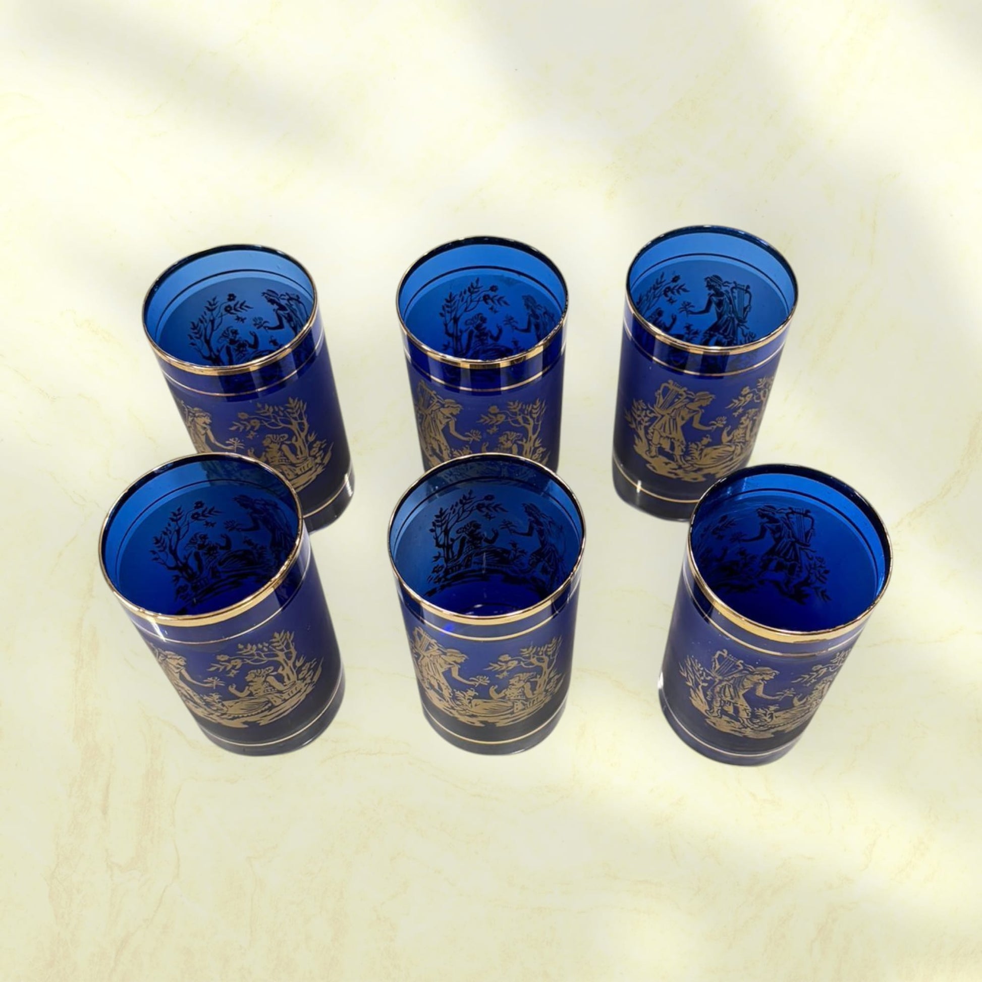 Botella de cristal cobalto con tapón esférico y ribetes dorados.